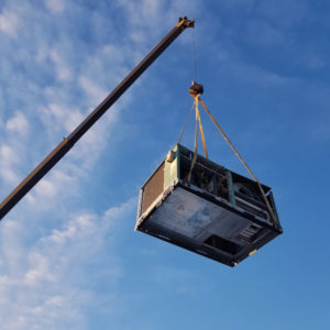 An old HVAC unit being lifted by a crane